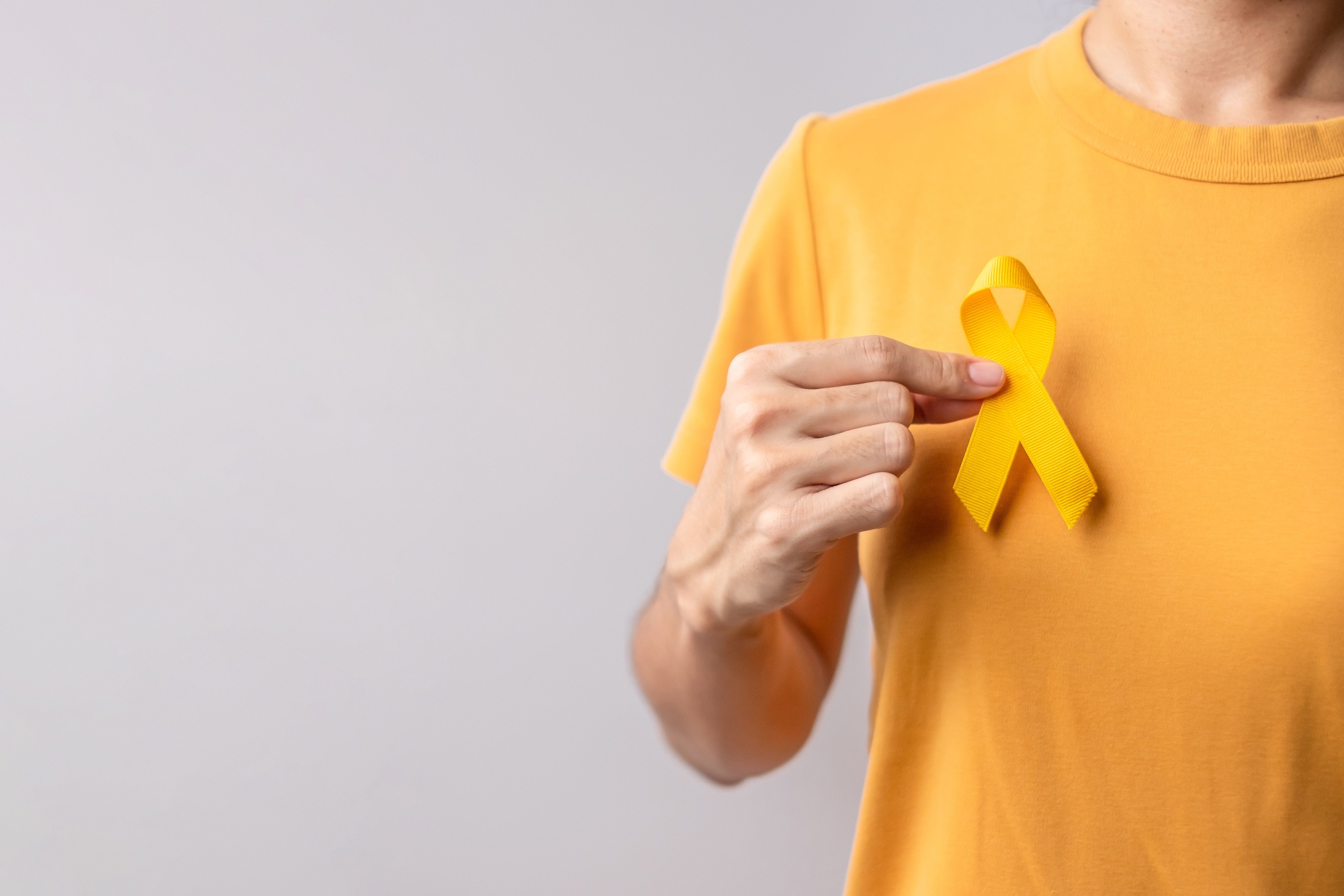 A person in yellow t-shirt holding a yellow ribbon.